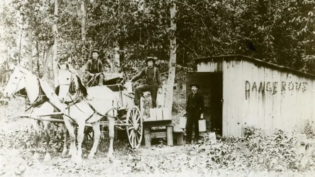 Teamsters with horse-drawn wagon haul nitroglycerin near a storage shed marked “Dangerous” in early Oklahoma oil field